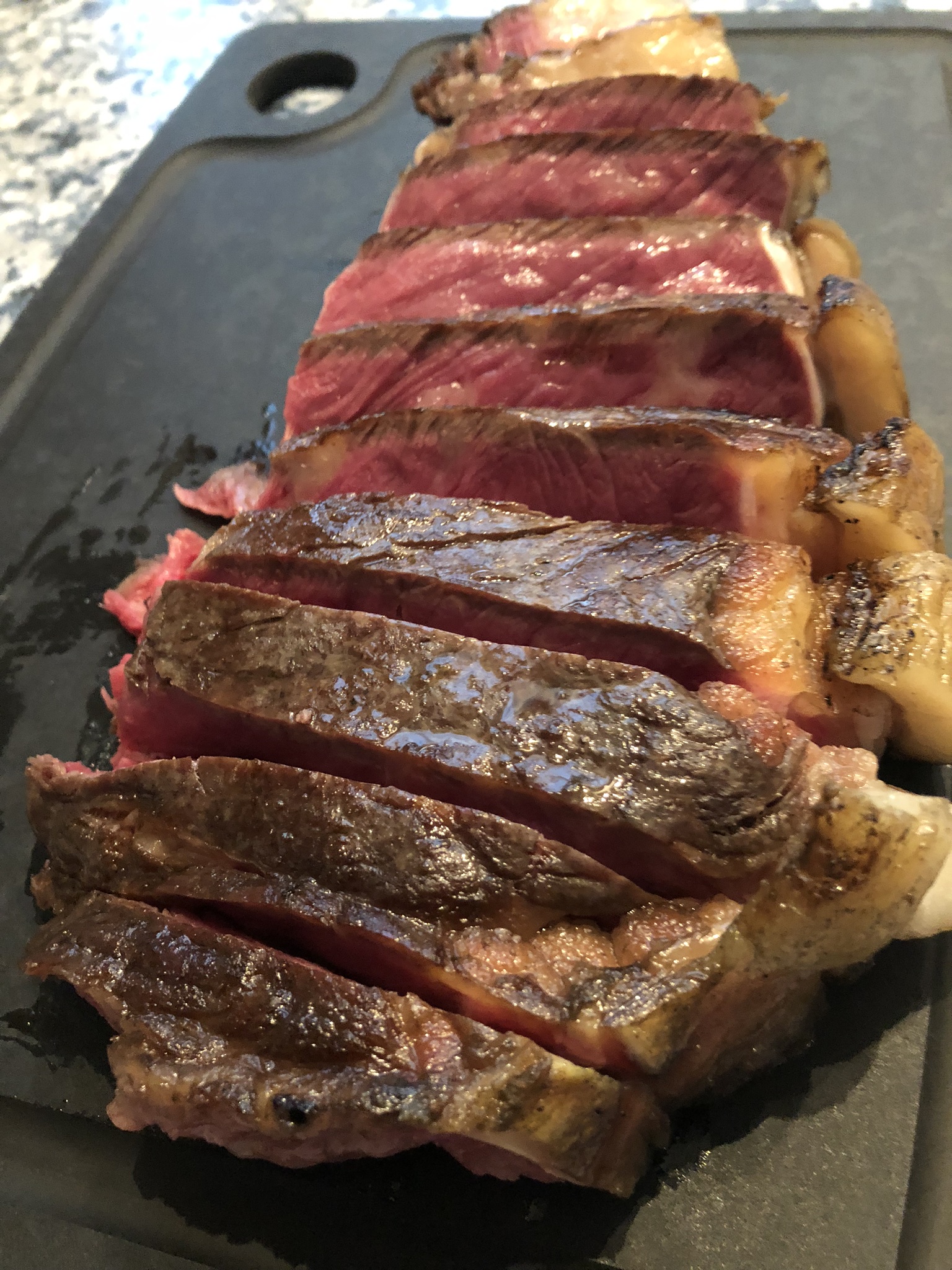 Steak in Scheiben auf einem dunklen Schneidebrett